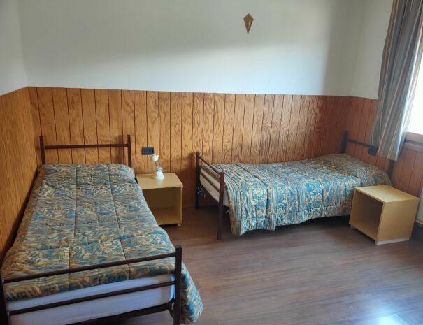 Camera da letto luminosa con due letti singoli e due comodini.