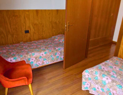 Camera con letti singoli, in legno, una poltrona.