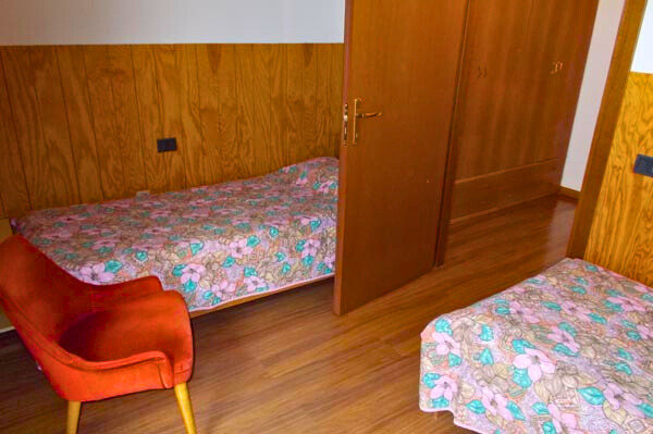 Camera con letti singoli, in legno, una poltrona.