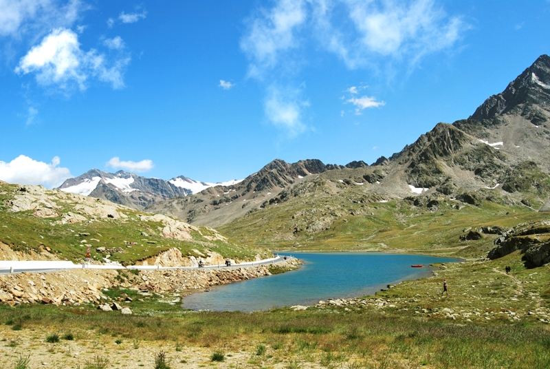 Estate a Valfurva: ampi prati verdi e lago turchese.