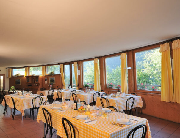 Sala ristorante molto luminosa con tavoli apparecchiati. Le ampie vetrate mostrano il panorama esterno.