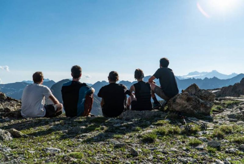 Ragazzi di un oratorio seduti a contemplare il bellissimo paesaggio di montagna che hanno di fronte.