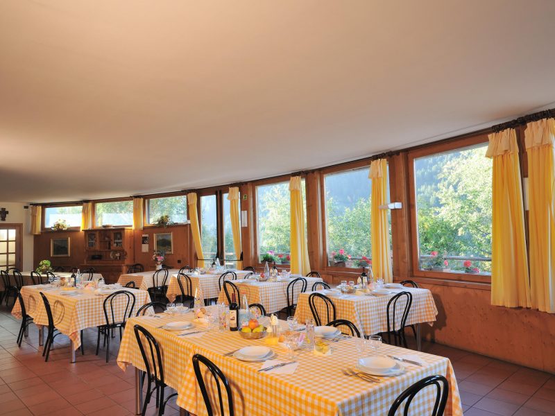 Sala ristorante molto luminosa con tavoli apparecchiati. Le ampie vetrate mostrano il panorama esterno.